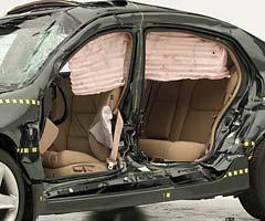 View of the vehicle after the crash with doors removed, showing the side airbags and damage to the occupant compartment