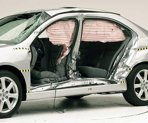 View of the vehicle after the crash with doors removed, showing the side airbags and damage to the occupant compartment