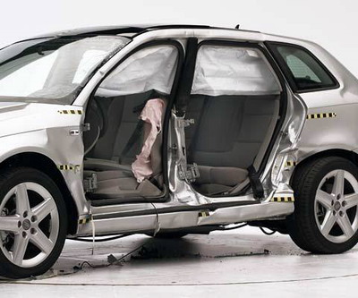 View of the vehicle after the crash with doors removed, showing the side airbags and damage to the occupant compartment