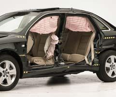 View of the vehicle after the crash with doors removed, showing the side airbags and damage to the occupant compartment