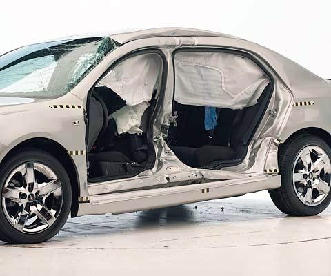 View of the vehicle after the crash with doors removed, showing the side airbags and damage to the occupant compartment.