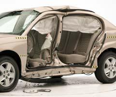 View of the vehicle after the crash with doors removed, showing the side airbags and damage to the occupant compartment.