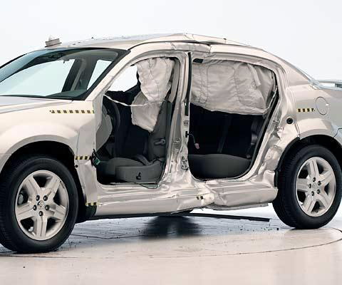 View of the vehicle after the crash with doors removed, showing the side airbags and damage to the occupant compartment