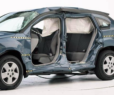 View of the vehicle after the crash with doors removed, showing the side airbags and damage to the occupant compartment