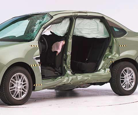 View of the vehicle after the crash with doors removed, showing the side airbags and damage to the occupant compartment