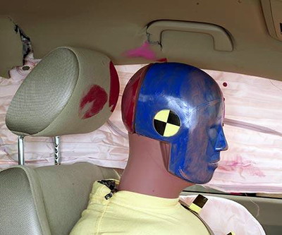 Smeared greasepaint indicates where the dummy's head contacted the side curtain airbag, dislodged roof rail trim, and head restraint during rebound