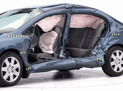 View of the vehicle after the crash with doors removed, showing the side airbags and damage to the occupant compartment