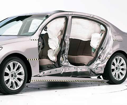 View of the vehicle after the crash with doors removed, showing the side airbags and damage to the occupant compartment (second test shown)