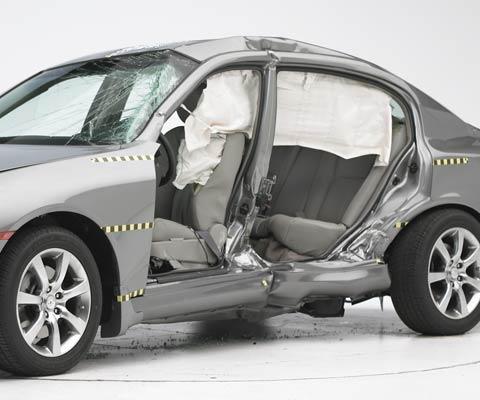 View of the vehicle after the crash with doors removed, showing the side airbags and damage to the occupant compartment