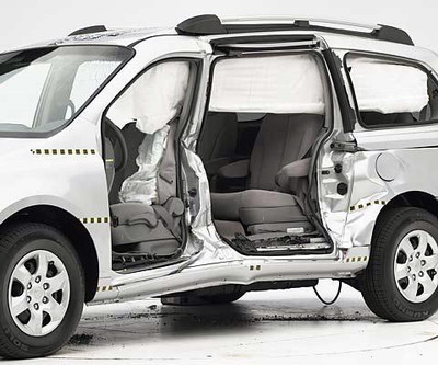 View of the vehicle after the crash with doors removed, showing the side airbags and damage to the occupant compartment.