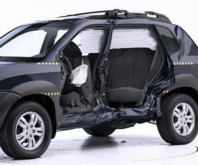 View of the vehicle after the crash with doors removed, showing the side airbags and damage to the occupant compartment