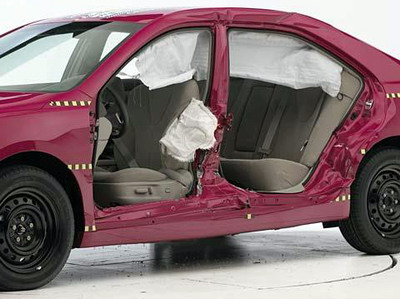 View of the vehicle after the crash with doors removed, showing the side airbags and damage to the occupant compartment