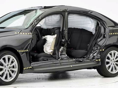 View of the vehicle after the crash with doors removed, showing the side airbags and damage to the occupant compartment.