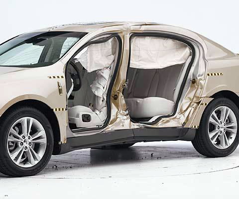 View of the vehicle after the crash with doors removed, showing the side airbags and damage to the occupant compartment