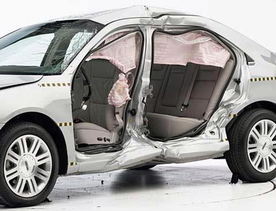 View of the vehicle after the crash with doors removed, showing the side airbags and damage to the occupant compartment