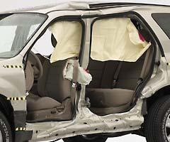 View of the vehicle after the crash with doors removed, showing the side airbags and damage to the occupant compartment