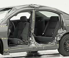 View of the vehicle after the crash with doors removed, showing damage to the occupant compartment