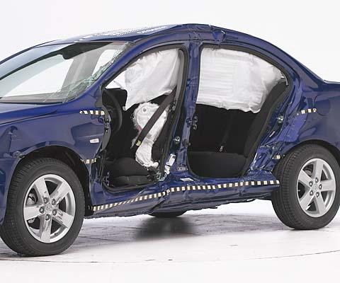 View of the vehicle after the crash with doors removed, showing the side airbags and damage to the occupant compartment