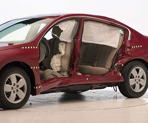 View of the vehicle after the crash with doors removed, showing the side airbags and damage to the occupant compartment