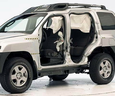 View of the vehicle after the crash with doors removed, showing the side airbags and damage to the occupant compartment