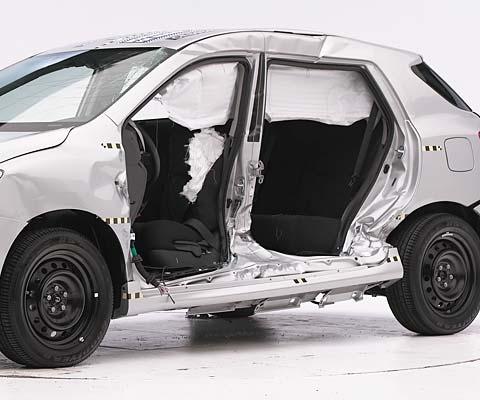 View of the vehicle after the crash with doors removed, showing the side airbags and damage to the occupant compartment