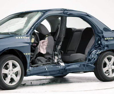 View of the vehicle after the crash with doors removed, showing the side airbags and damage to the occupant compartment.