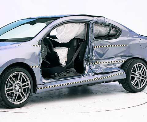 View of the vehicle after the crash with doors removed, showing the side airbags and damage to the occupant compartment