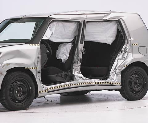 View of the vehicle after the crash with doors removed, showing the side airbags and damage to the occupant compartment