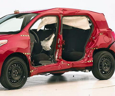 View of the vehicle after the crash with doors removed, showing the side airbags and damage to the occupant compartment