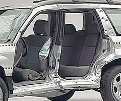 View of the vehicle after the crash with doors removed, showing the side airbag and damage to the occupant compartment