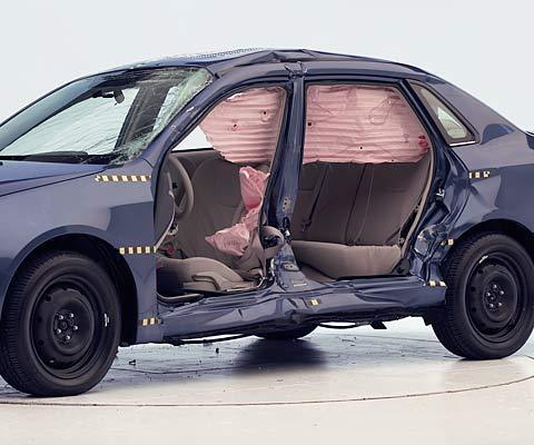 View of the vehicle after the crash with doors removed, showing the side airbags and damage to the occupant compartment