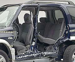 View of the vehicle after the crash with doors removed, showing damage to the occupant compartment