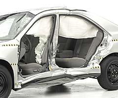 View of the vehicle after the crash with doors removed, showing damage to the occupant compartment