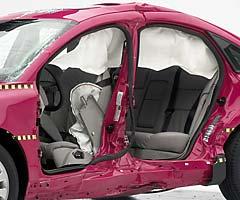 View of the vehicle after the crash with doors removed, showing the side airbags and damage to the occupant compartment