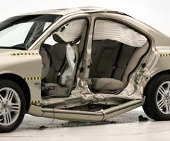 View of the vehicle after the crash with doors removed, showing the side airbags and damage to the occupant compartment