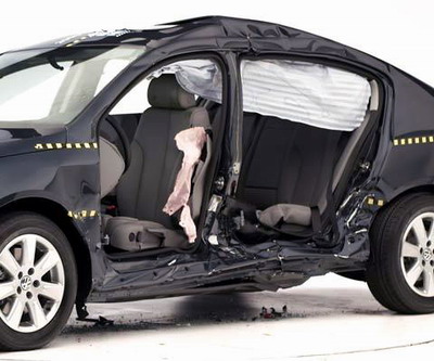 View of the vehicle after the crash with doors removed, showing the side airbags and damage to the occupant compartment